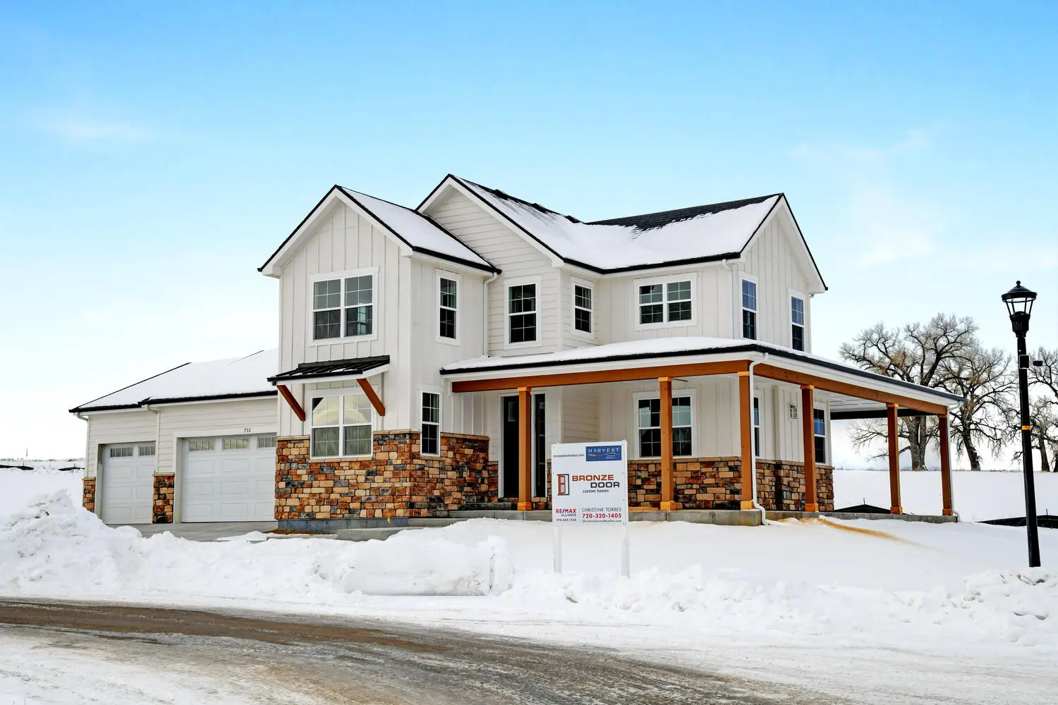 a large house with white exteriors and its yard covered with snow
