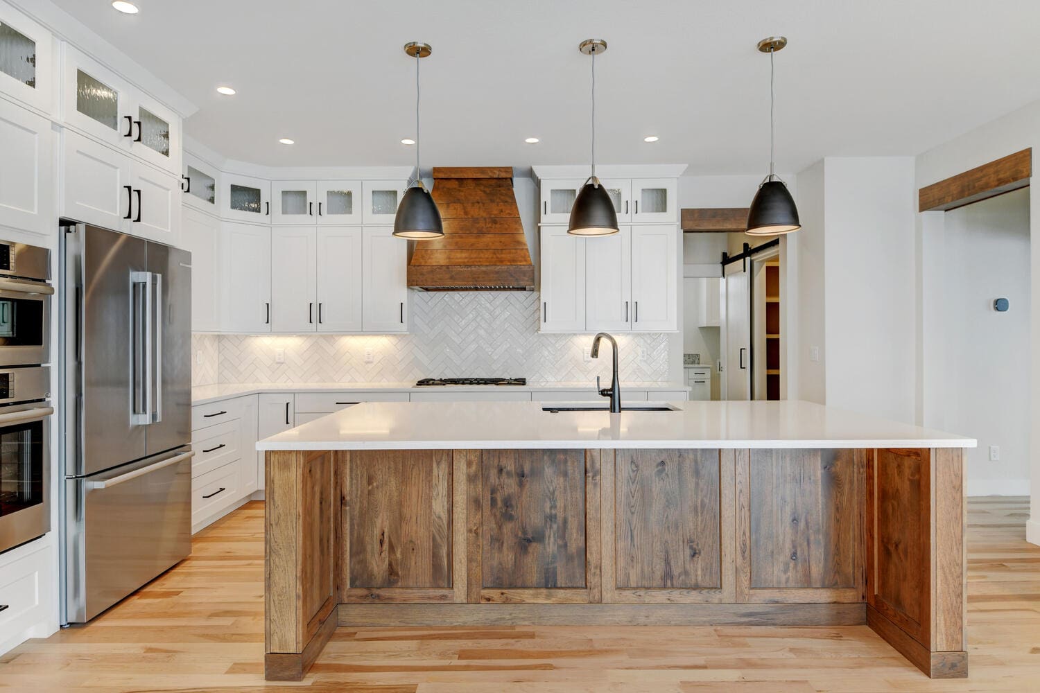 a spacious kitchen with white cupboards and counters, an island, and modern appliances