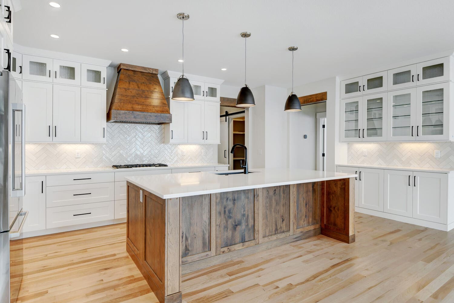 a kitchen with white walls, cupboards, and counters and an island counter