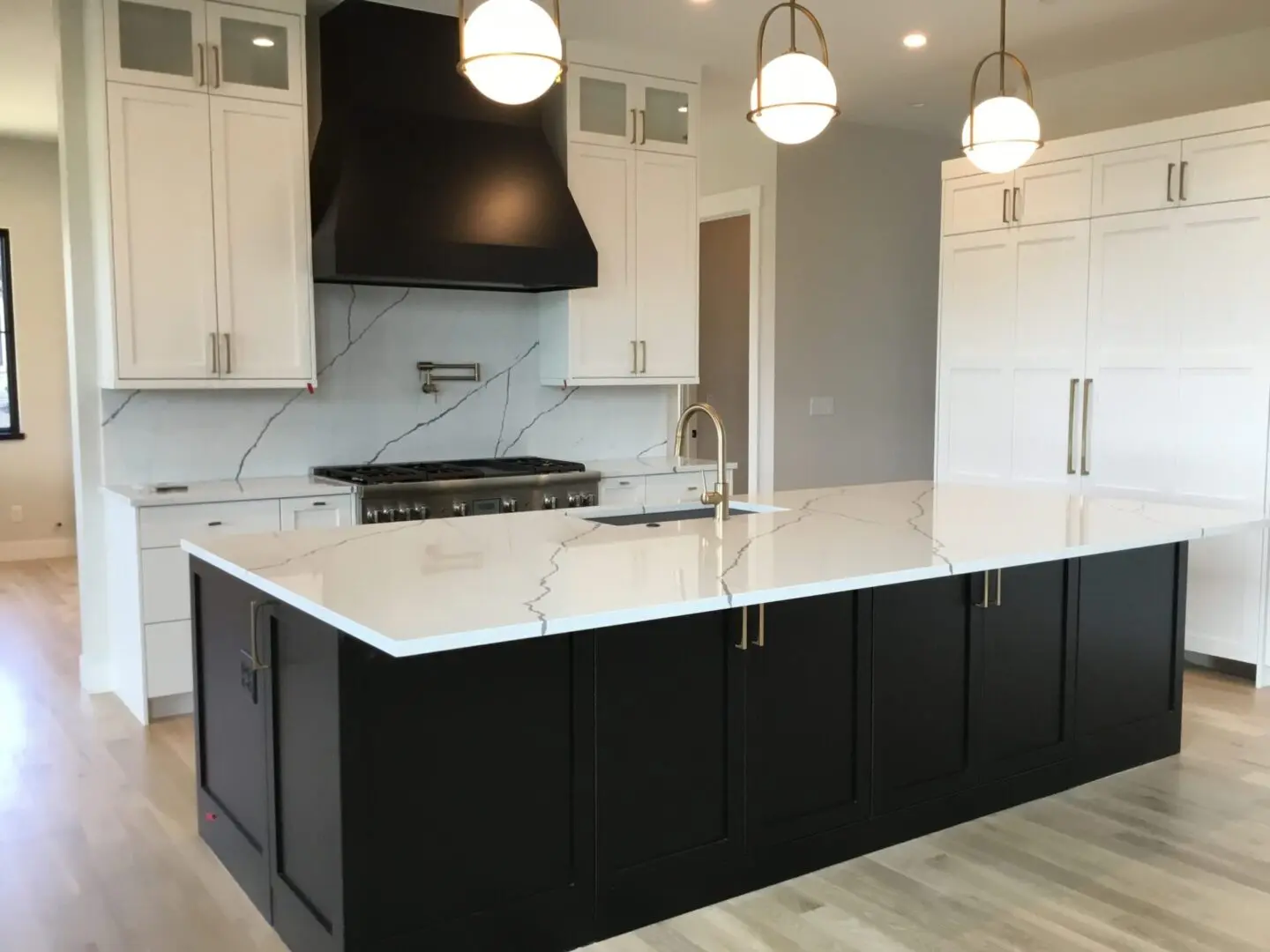 a kitchen with white cupboards and a black island counter with a sink