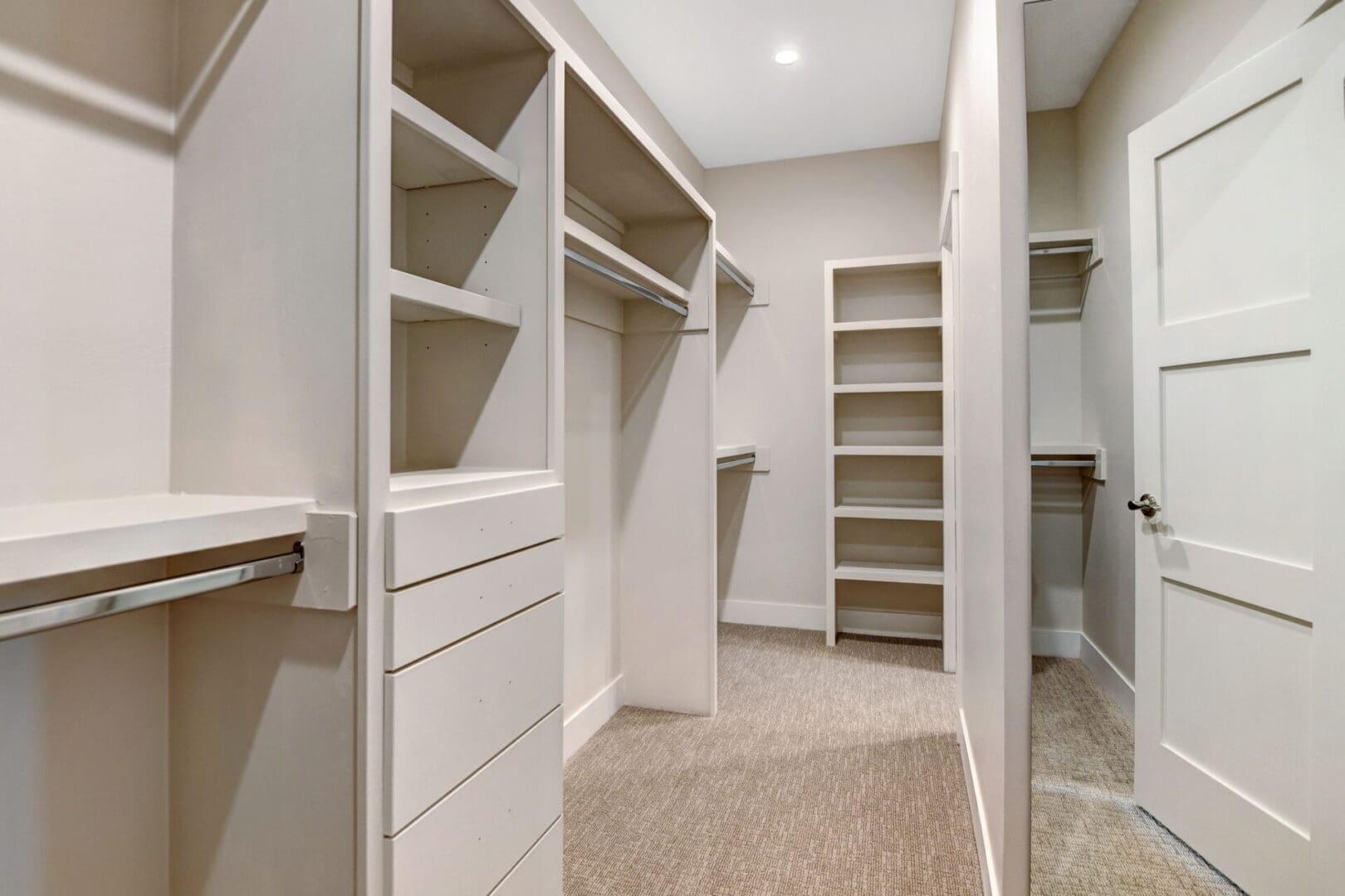 A walk in closet with shelves and drawers